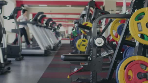 A rapariga corre numa passadeira no ginásio. Saúde e fitness. Exercícios e Práticas. Exercícios individuais de perda de peso para a mulher. Aqueça antes do treino por senhora grossa. Treino em uma sala de esporte — Vídeo de Stock