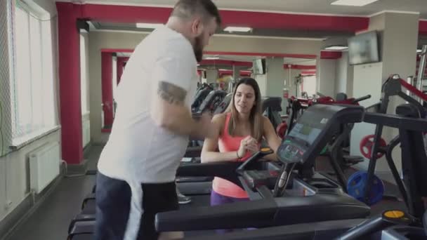 Guy körs på löpband i gymmet. Viktminskning borrar från privat tränare för fat man. Hälsa och gym. Övningar och praktik. Värm upp innan träningen av tjocka person. Personlig instruktör — Stockvideo