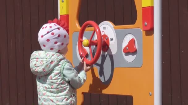 Una hermosa niña caucásica de 3 años juega en un moderno parque infantil nuevo y multicolor en un día de primavera, al aire libre — Vídeo de stock