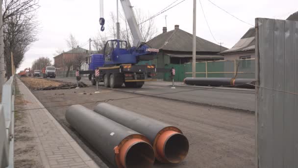 工程在城市更换和拆卸管道的供热主，起重机升降机新的管道铺设在道路下，工业 — 图库视频影像