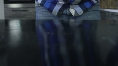 Closeup Bir adam masaya deterjan püskürter ve iyice mutfakta bir viskon bez ile yüzey ilerler. Bir adam indüksiyon ocak üzerinde temizlik maddesi sıçramaları ve özenle bir elektrik sürtünme