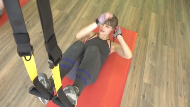 Hermosa chica caucásica entrenador profesional realiza ejercicios difíciles en las bisagras TRX — Vídeo de stock