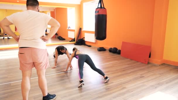 En fyllig kille och en smal tjej. Personlig boxningsträning i Fitness Club eller gym. Styrka övningar och praktik. Individuella vikt förlust övningar. Coach förklaring och hälsa. Slow motion — Stockvideo