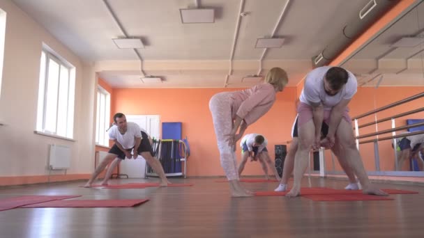 Piękna kaukaski kobieta instruktor uczy technik jogi w męskiej sesji grupowej. wzmocnienie mięśni i zdrowia z asany w Joga, nowoczesne centrum fitness — Wideo stockowe