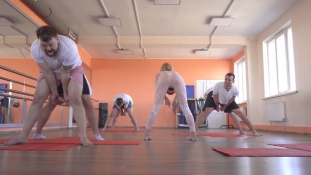 Hermosa instructora caucásica enseña técnicas de yoga en una sesión grupal masculina. fortalecer el músculo y la salud con asanas en yoga, gimnasio moderno, entrenador — Vídeo de stock
