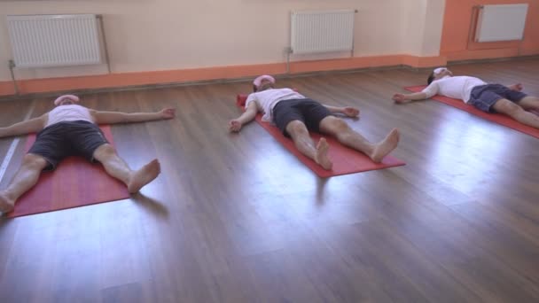 Kaukasisk kvinna instruktör genomför yogaklasser, Shavasana hållning, manliga vänner ligg och slappna av, restaurering och förnyelse av hela organismen, en känsla av lätthet och frid, hälsosam livsstil — Stockvideo