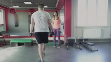 Spor salonunda erkek için kız antrenörü ile bireysel eğitim. Özel eğitmen ile Kalın obez adam fitness merkezinde fiziksel pislikler ve egzersizler yapmak. Kilolu kişi ve kadın egzersiz ile kalori yakmak.