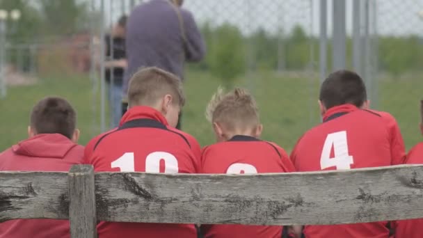 Rapazes jogadores de futebol em uniforme sentar-se no banco, futebol, profissional — Vídeo de Stock