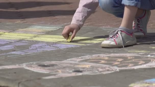 The girl draws with multi-colored crayons on the paving slabs, close-up — Stock Video