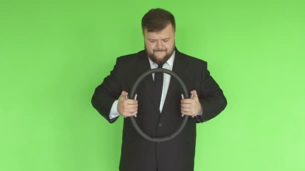 En kaukasisk man med skägg kontorsarbetare i kostym med skägg pressar en sportexpander mot bakgrund av en grön vägg, sportkläder — Stockvideo