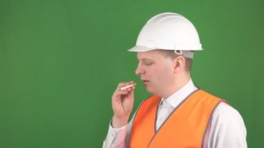 Sinyal yeleği ve koruyucu kasklı beyaz bir adam işyerinde sigara içmek istiyor, işyeri güvenliği ve yangınları kavramı, hromakey