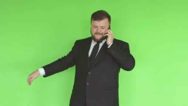 Young caucasian male businessman with a beard and in a suit twirling a hoop in the gym and talking on the phone against a green wall, healthy lifestyle — Stock Video