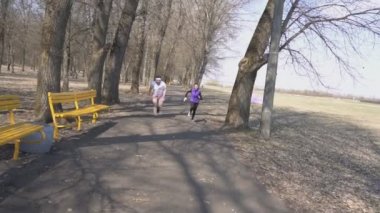 Genç sakallı adam ve ince kız antrenör bir yarış, sağlıklı bir yaşam tarzı, bahar, yavaş hareket parkta çalıştırmak