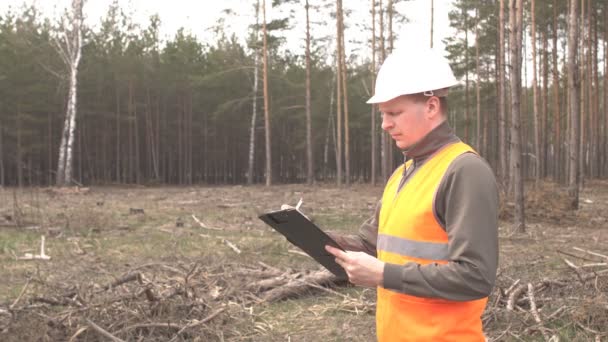 Ένας νεαρός λευκός επιθεωρητής γράφει ένα δάσος και αποψίλωση, τοπίο — Αρχείο Βίντεο