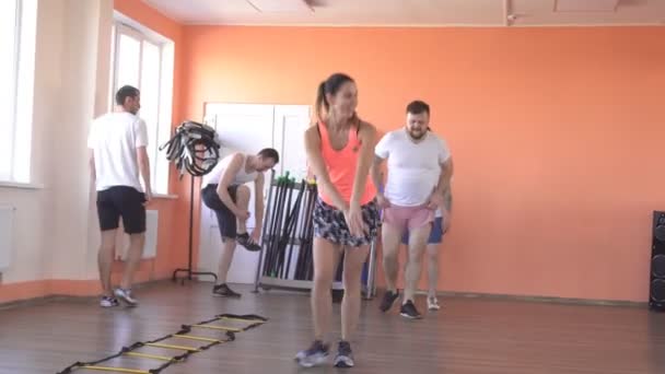 Красивая кавказская девушка-тренер показывает мужчинам упражнения для похудения и здоровья в современном фитнес-центре, групповые занятия в тренажерном зале — стоковое видео
