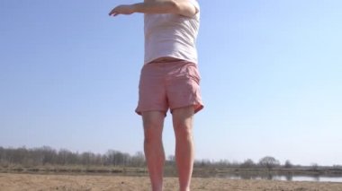 Sakallı beyaz bir adam nehrin kıyısında dinamik yoga yapıyor, kumlu bir plaj, ellerinin bir uzantısı, bahar