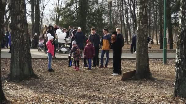 BOBRUISK, BELARUS 03.09.19: Los niños pequeños y los padres juegan juegos tradicionales lanzando botas en el parque de primavera. Los niños pequeños compiten entre sí tirando zapatos en el parque de la ciudad en la primavera . — Vídeos de Stock