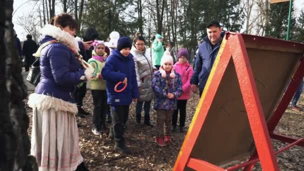 Bobruisk, Bělorusko 03.09.19: malý chlapec během jarního festivalu hází na hřebíčky do městského parku barevný poskok. Mladý chlápek vrhá na jaře v parku barevné kroužky na kolíky. — Stock video