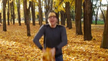 Komik adam akçaağaç yaprakları bir demet atar ve sonbahar parkı bir köpek gibi mutlu. Güneşli bir günde bir kasabada yaprak düşer. Güzel doğa