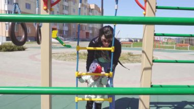 Küçük güzel beyaz kız 3 yaşında çocuklar için modern bir oyun alanında annesi ile oynar, spor ekipmanları