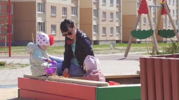 Pouco bela menina caucasiana 3 anos de idade joga no parque infantil na caixa de areia, maternidade — Vídeo de Stock