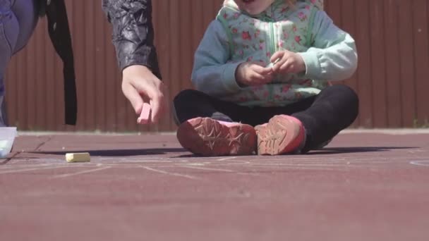 Hermosa madre caucásica dibuja con lápices de colores con su hija pequeña de 3 años en el patio de recreo, juego — Vídeos de Stock