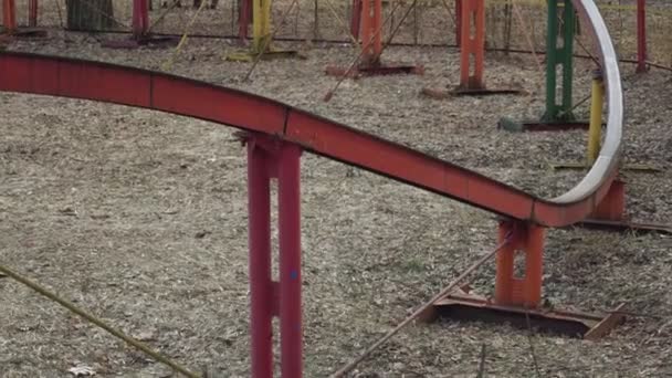 Closeup the wheels of the old diminutive rollercoaster pass on the rail in the amusement park. People in booths ride in a circle. — Stock Video