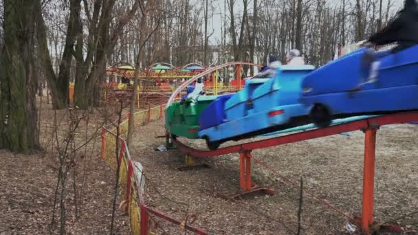 Die alte Mini-Achterbahn im Vergnügungspark fährt im Kreis. Budenbesucher haben Spaß und freuen sich. — Stockvideo