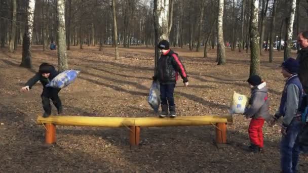 БОБРУЙСК, БЕЛАРУСЬ, 19 мая.: Дети веселятся в парке во время Масленицы. Мальчики играют друг с другом на детской площадке. Весной праздник делает людей счастливее. Начало Масленицы . — стоковое видео