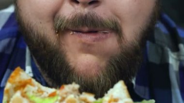 Aşırı kilolu bir adam hamburgerini yiyor. Adam ev yapımı yemeklerden hoşlanır. Sağlıksız Lifestyle, kızarmış ve zararlı yüksek kalori Gıda. Obezite ve kilolu riski. Yavaş hareket.