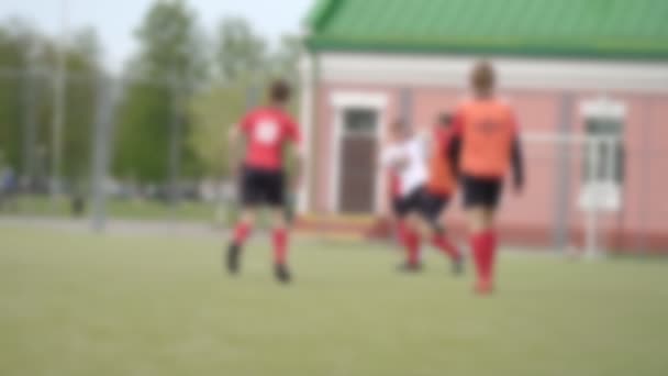 Jóvenes con uniforme rojo corren alrededor del estadio jugando al fútbol, lento mo, borroso, fondo — Vídeos de Stock