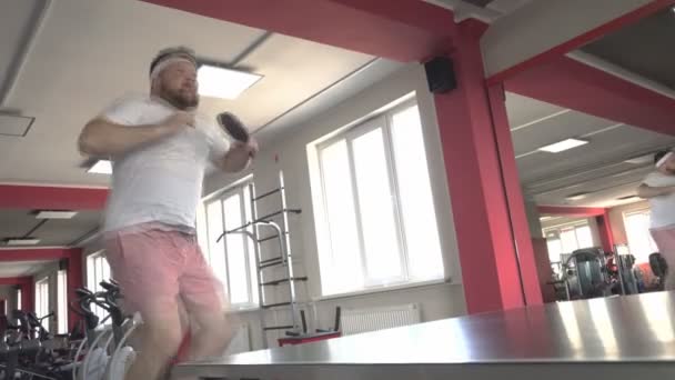 Fat bearded caucasian man plays table tennis and performs the jump exercise for weight loss, model — Stock Video
