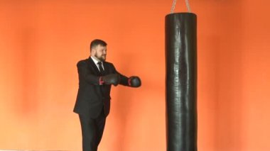 Boks eldiven şef veya patron spor salonunda yumruk torbası yendi. Takım işadamı yavaş hareket fitness kulübünde stres hafifletir. Sakallı tombul müdür spor merkezinde. Siyah ceket şişman adam