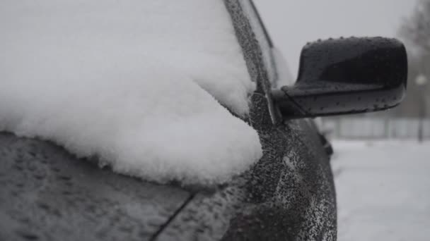 Schneeregen schmilzt im Winter auf der Motorhaube eines modernen schwarzen Autos — Stockvideo