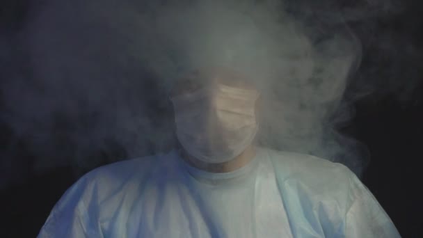 Лікар хірург стоїть в диму на чорному тлі концепція хвороб від куріння і спаленого диму, повільний рух — стокове відео