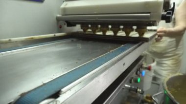 Şekerleme fabrikasında muhallebi kek yapmak için ekipman. Taze hamur tava üzerinde pişirme ekipmanları üzerinden geçer, Şarküteri