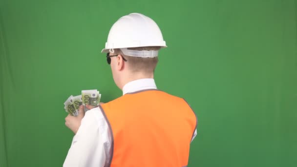Šéf ve stavební helmě a signální vesta po úspěšné transakci, zelené pozadí, hromu počítá peníze z eura. — Stock video