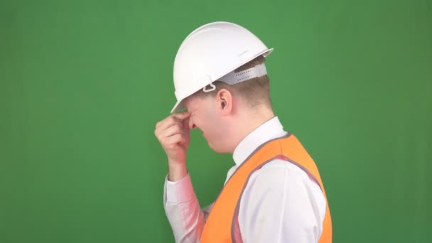 Caucásico jefe masculino en un casco blanco y un chaleco de señal que sostiene su cabeza después del estrés y la tensión en el lugar de trabajo, hromakey, fondo verde — Vídeos de Stock