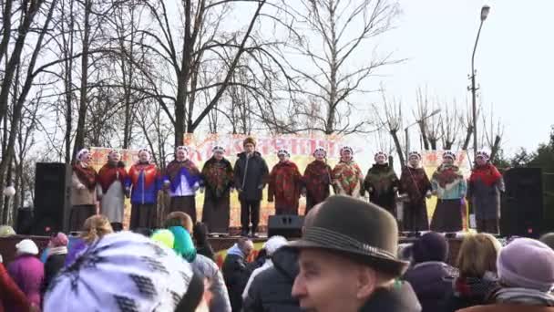 BOBRUISK, BELARUS 03.09.19: Elderly people in traditional kerchiefs sing on stage in front of a crowd in the city park during Shrovetide. Senior citizens in national dress perform on scene in front of — Stock Video