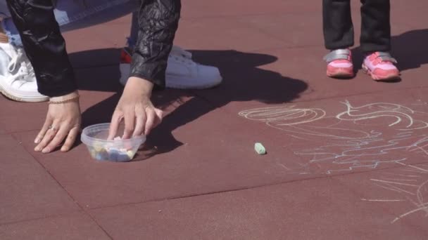 Bella madre caucasica disegna con pastelli con la sua bambina di 3 anni nel parco giochi, giocoso — Video Stock