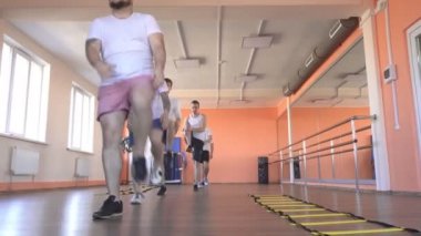 Güzel beyaz kız eğitmen modern bir fitness merkezinde kilo kaybı ve sağlık için erkekler egzersizleri gösterir, spor salonunda grup sınıfları