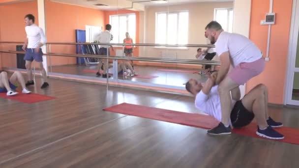 Paarweise Kurse in einem modernen Fitnesscenter mit kaukasischen Jungs, Gruppensport in der Turnhalle, um Muskeln zu stärken und Gewicht zu verlieren, Freundschaft — Stockvideo