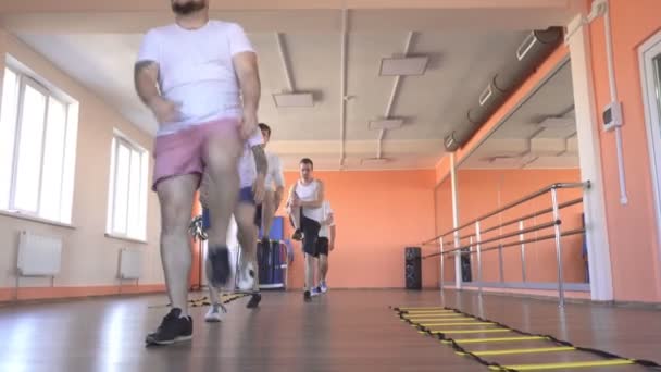 Hermosa chica caucásica entrenador muestra los hombres ejercicios para la pérdida de peso y la salud en un moderno gimnasio, clases en grupo en el gimnasio — Vídeo de stock