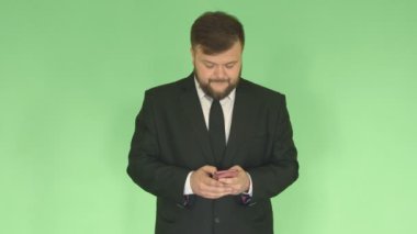 Bir takım elbiseli sakal ile beyaz bir adam posta kontrol eder ve bir akıllı telefonda Internet sosyal ağlarda iletişim kurar