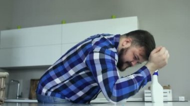 Şişman bir adam, mutfakta bir viskon bezi ile masayı siliyor. Bir adam mutfakta bir temizlik bezi ile masanın yüzeyini temizler.