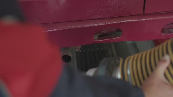 Pracownik stacji serwisowej umieszcza rurę na rurze wydechowej samochodu, aby zmierzyć dym i spaliny. — Wideo stockowe