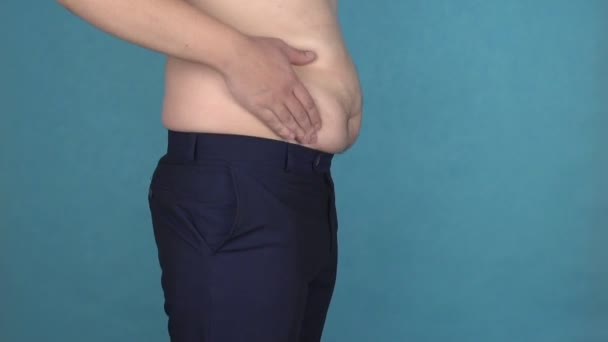 Homem com excesso de peso com barriga gorda toca e balança o abdômen em câmara lenta. Obesidade, corpo sem graça. Cara gorda ou grossa que come muita comida frita gordurosa e bebe cerveja. Saúde masculina e dieta. Cintura larga — Vídeo de Stock