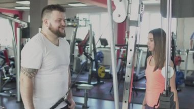 Bireysel antrenör ile kalın obez adam spor salonunda fiziksel gerizekalı yapmak. Kilolu adam ve kadın eğitmen kalori yakmak. Spor egzersizleri yapan kişisel eğitmen ile tombul erkek. Özel eğitim