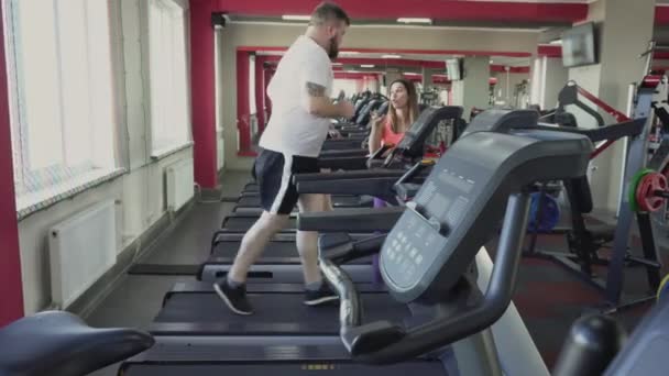男人在健身房的跑步机上跑步。减肥训练从私人教练为胖子。健康和健身。练习和练习。训练前热身由厚人。个人讲师 — 图库视频影像