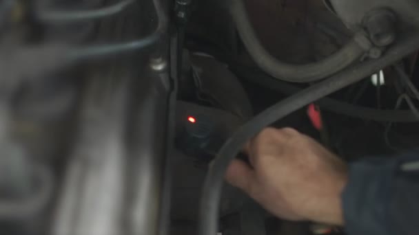 Ein Mann installiert einen Klopfsensor am Motor, um den Motor zu überprüfen und zu diagnostizieren, — Stockvideo